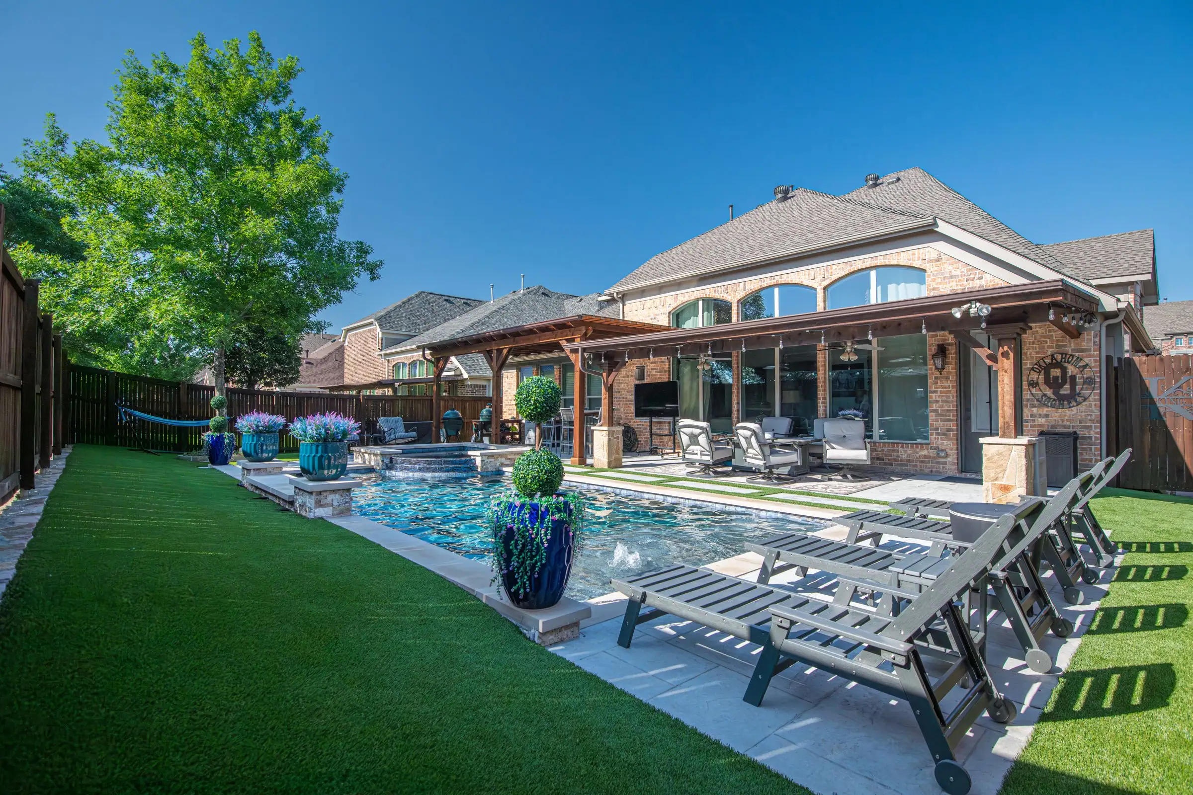 Backyard pool with lounge chairs and green grass along one side